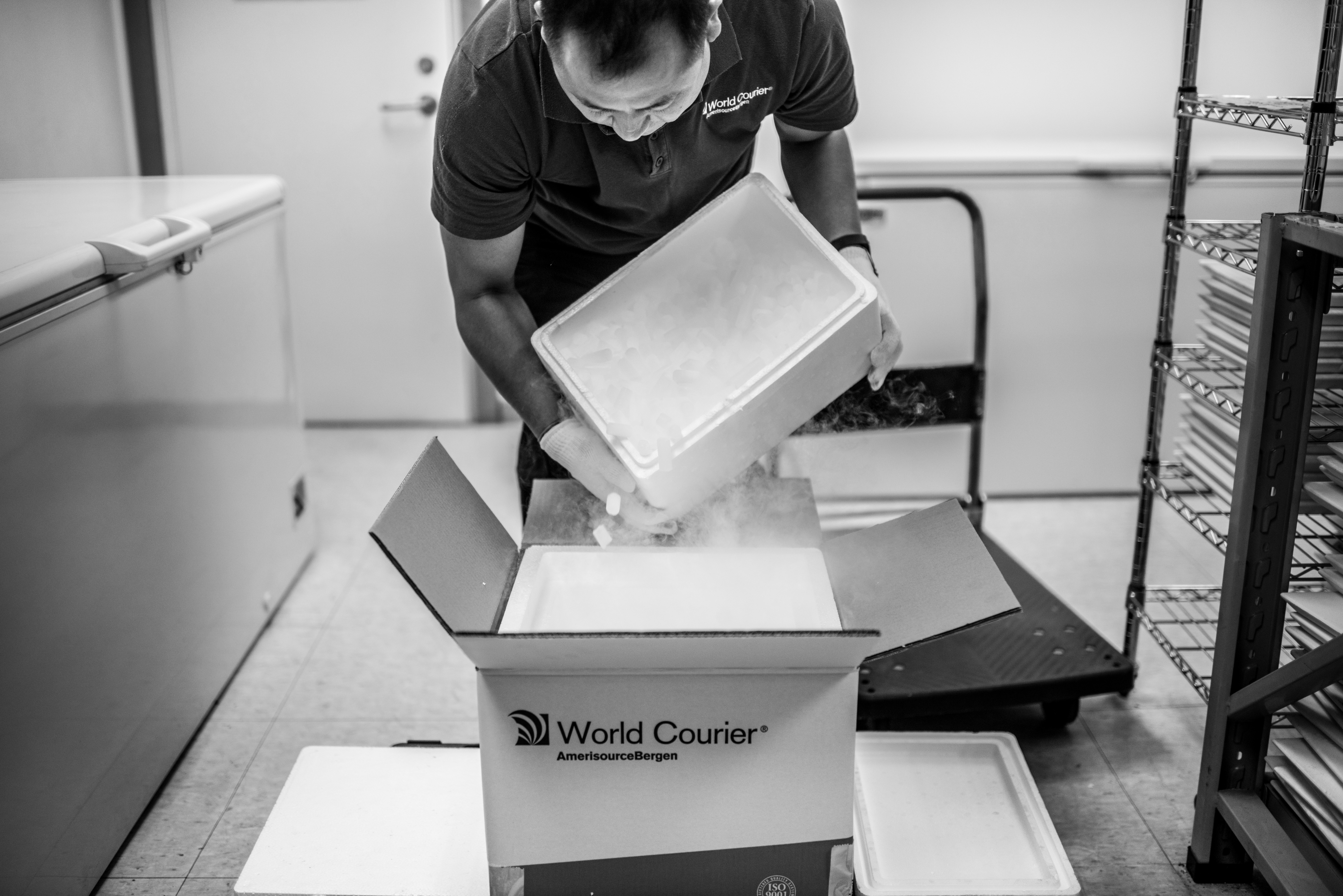 A World Courier associate places coolant inside an insulated package.