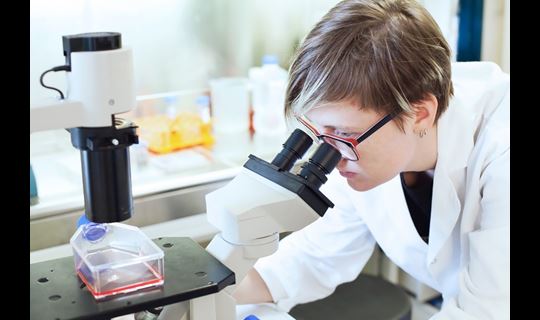 woman looking through microscope